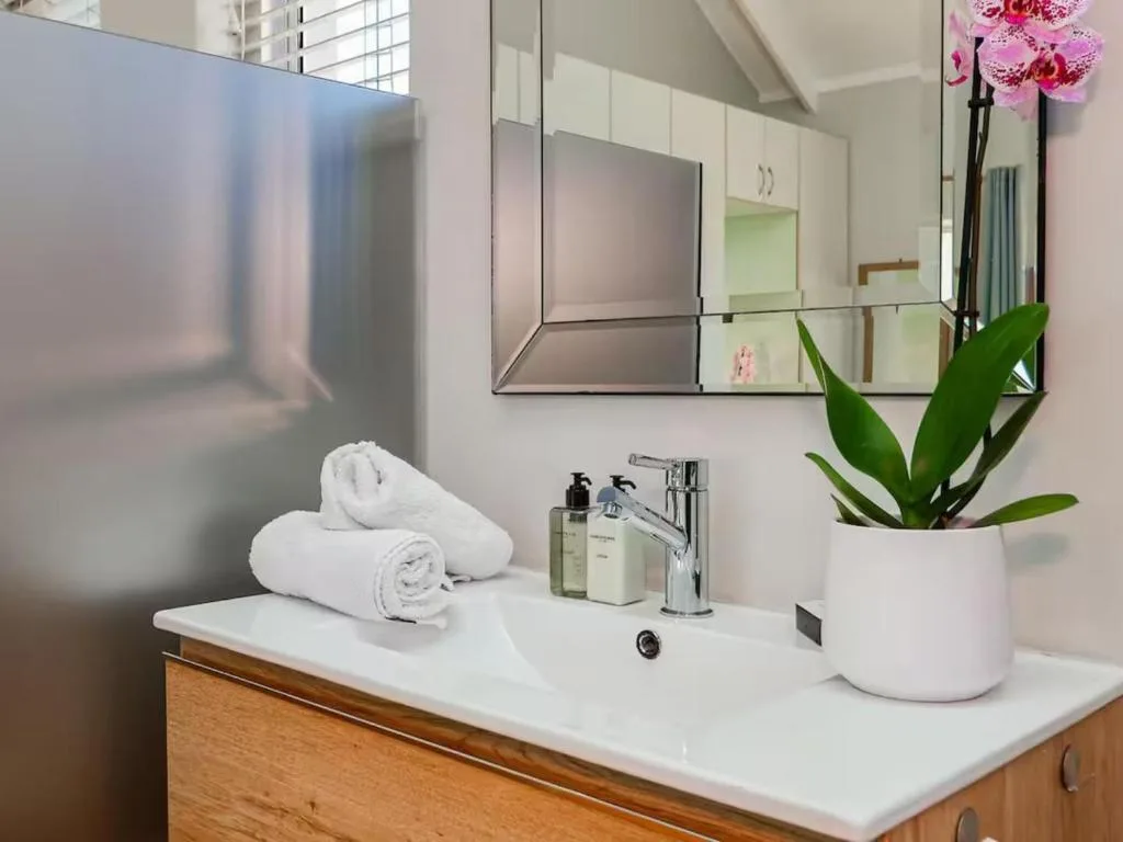 Modern bathroom vanity with white towels, orchid plant, and large mirror