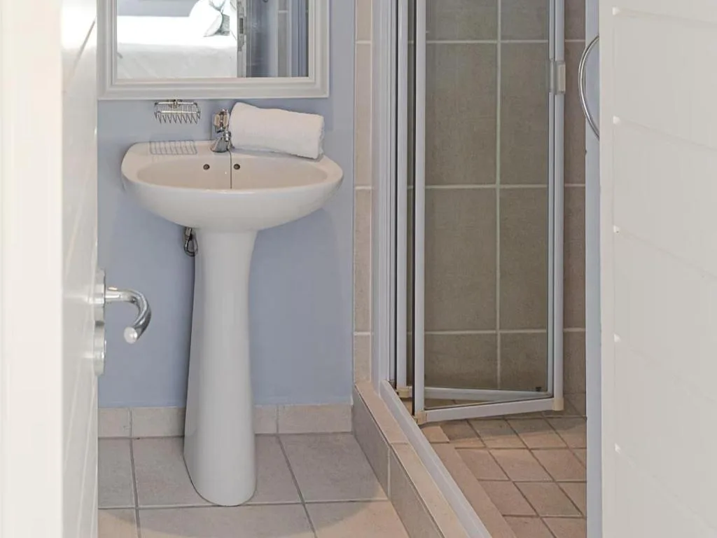 Clean bathroom with pedestal sink, mirror, and enclosed shower cubicle