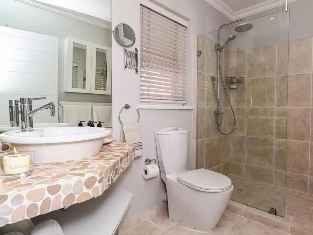 Modern bathroom with curved vanity, shower enclosure, toilet, and window