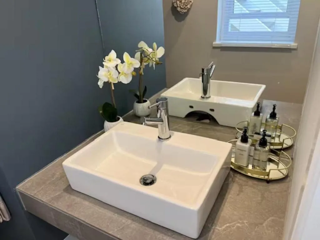 Modern bathroom vanity with dual white vessel sinks and chrome fixtures