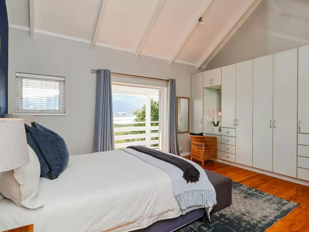 Spacious bedroom with queen bed, built-in wardrobes, and lagoon views