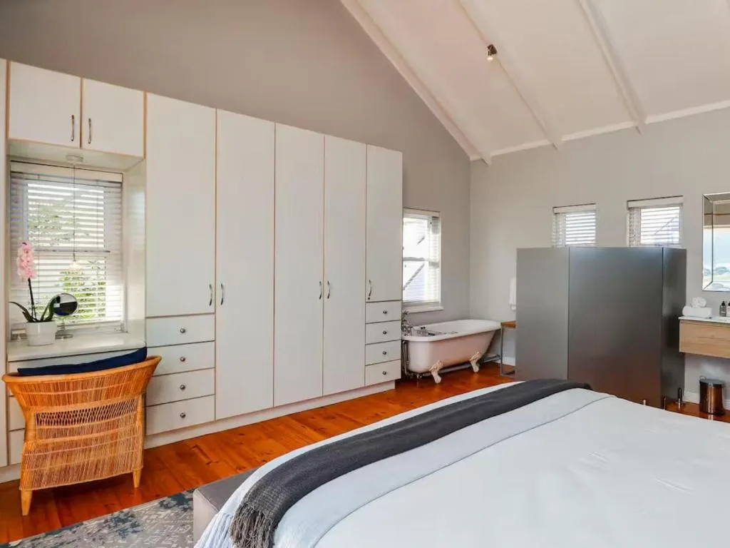 Spacious bedroom with queen bed, white cabinetry, and freestanding bathtub