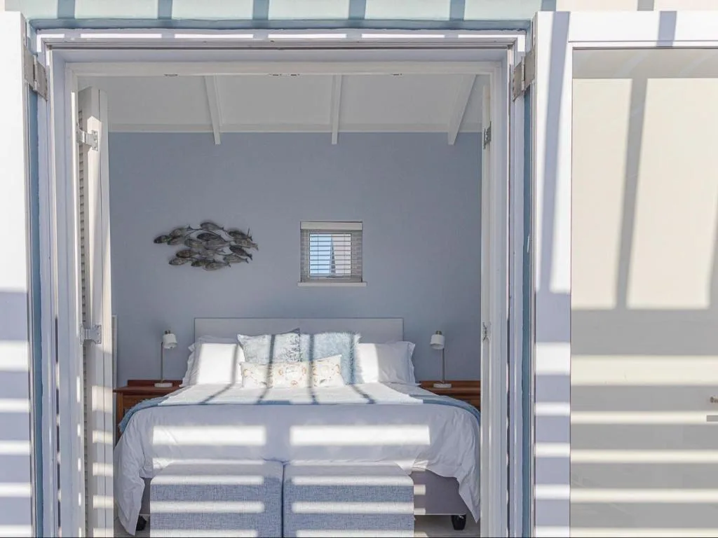 Bright bedroom with double bed, wooden nightstands, and coastal wall art