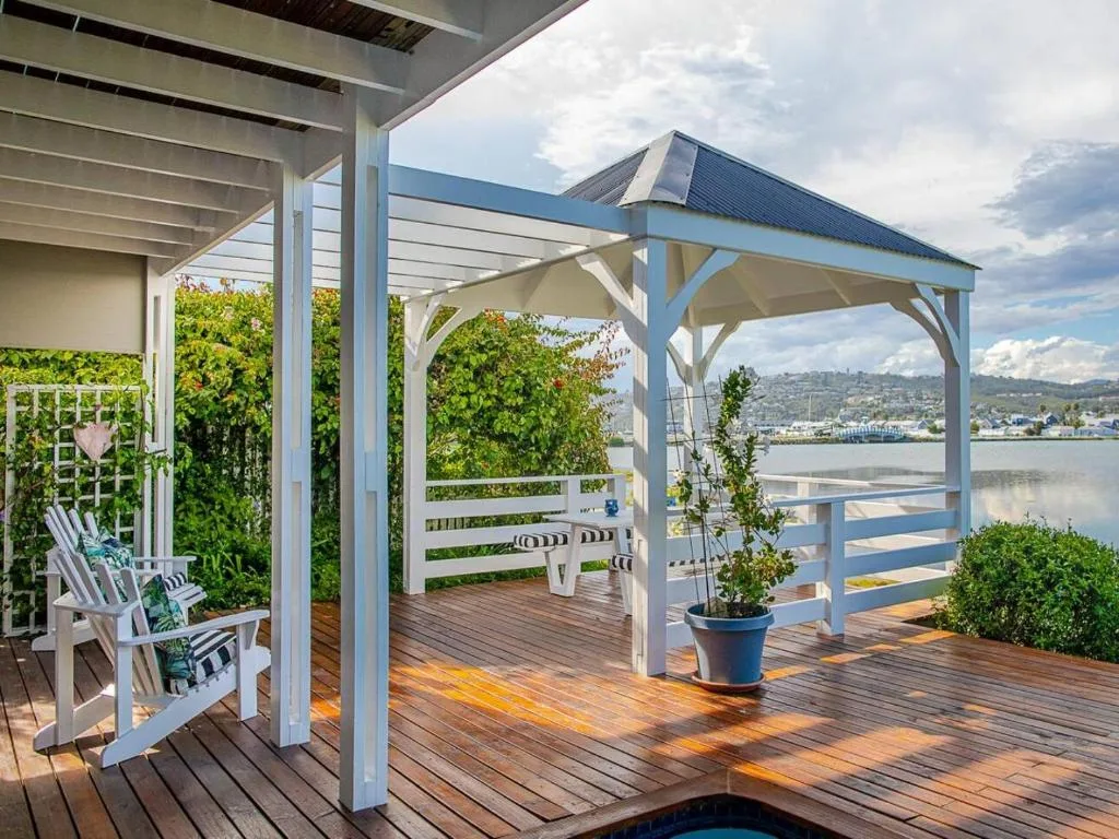 Wooden deck with pergola, white chairs, and lagoon views