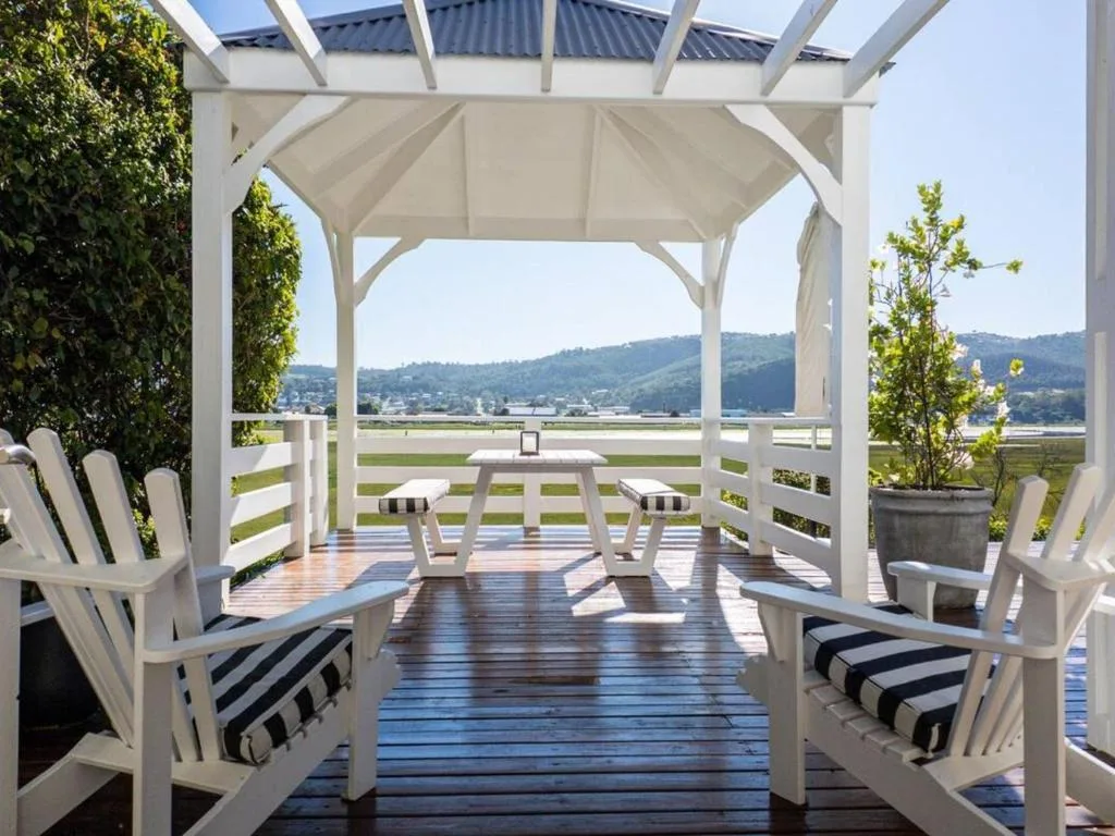 Wooden deck with pergola, Adirondack chairs, and mountain valley views