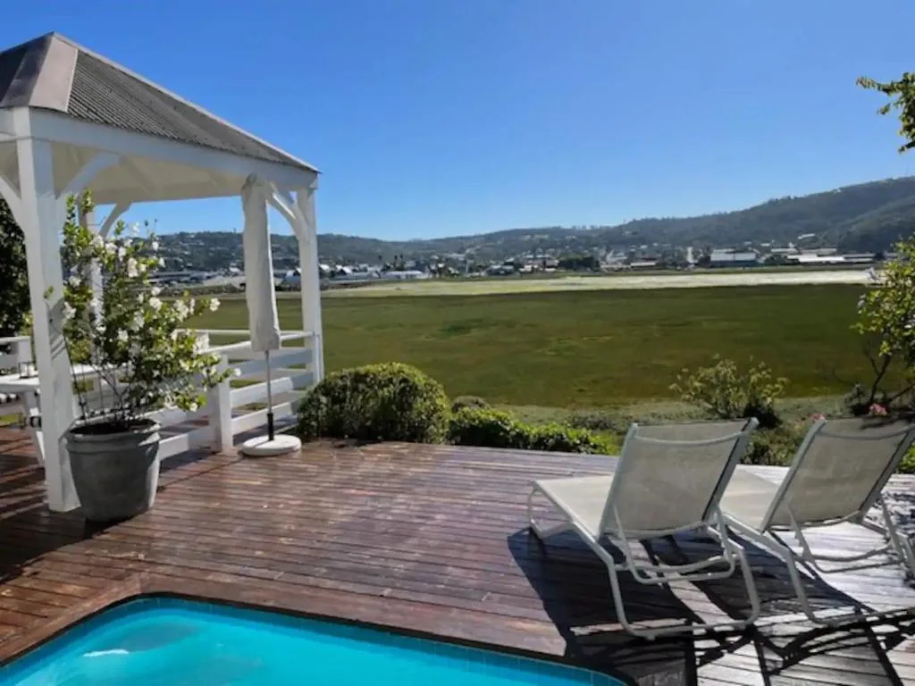 Wooden deck with pool, loungers, pergola, and sweeping valley views