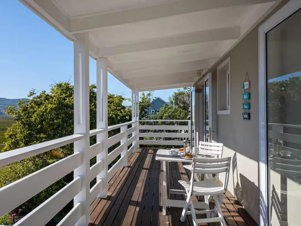 Covered deck with white railings, dining table, and mountain valley views