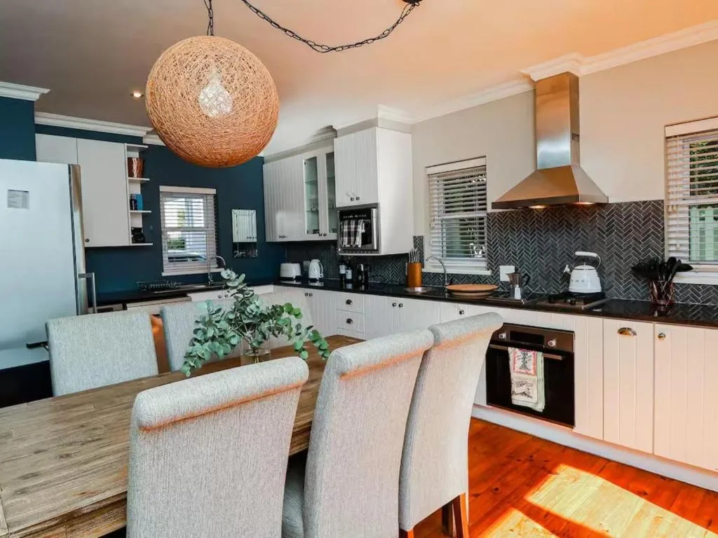 Modern kitchen with white cabinetry, dark herringbone backsplash, and dining table