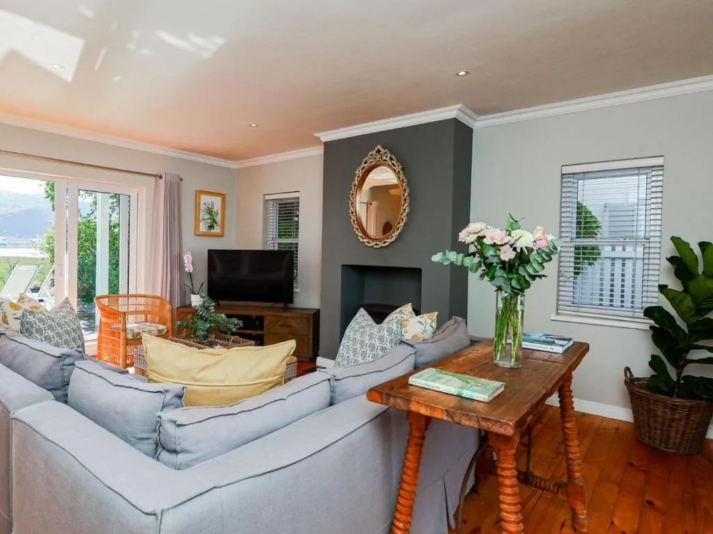 Spacious living room with gray sofas, fireplace, and garden views through doors