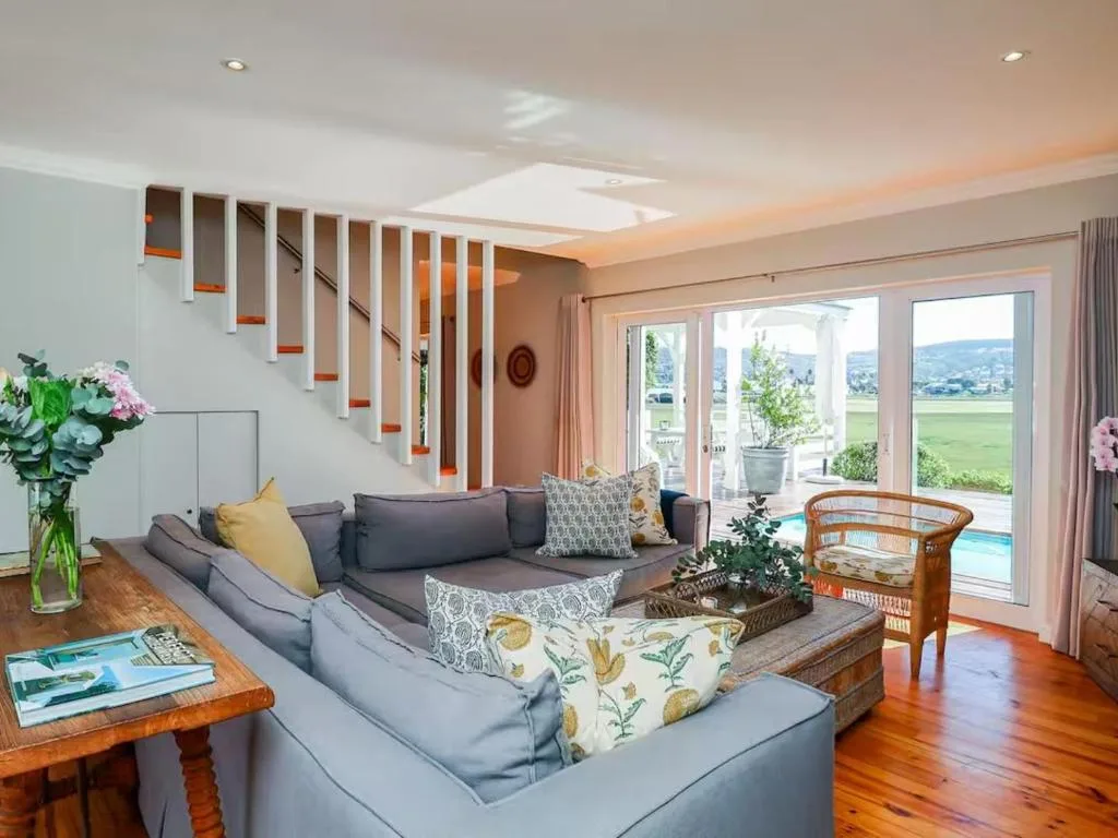 Spacious open-plan lounge with gray sectional sofa and scenic valley views through glass doors