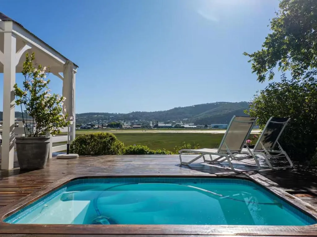 Crystal-clear pool with wooden deck, loungers, and valley views beyond