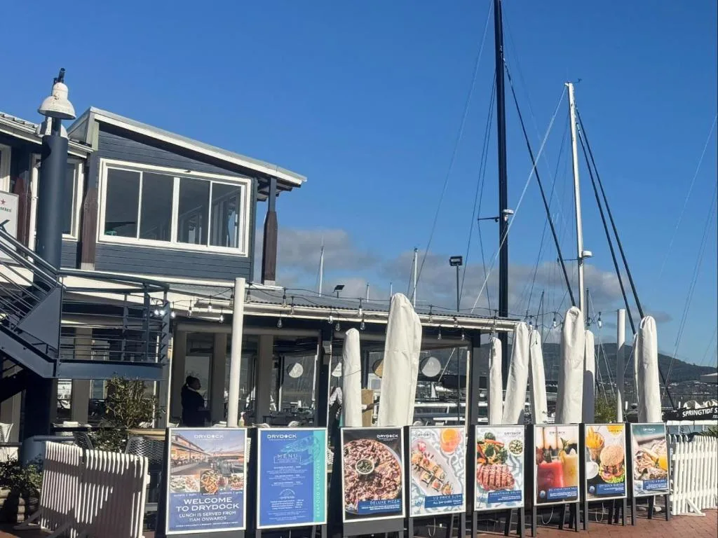 Modern waterfront building with large windows overlooking sailboats and marina