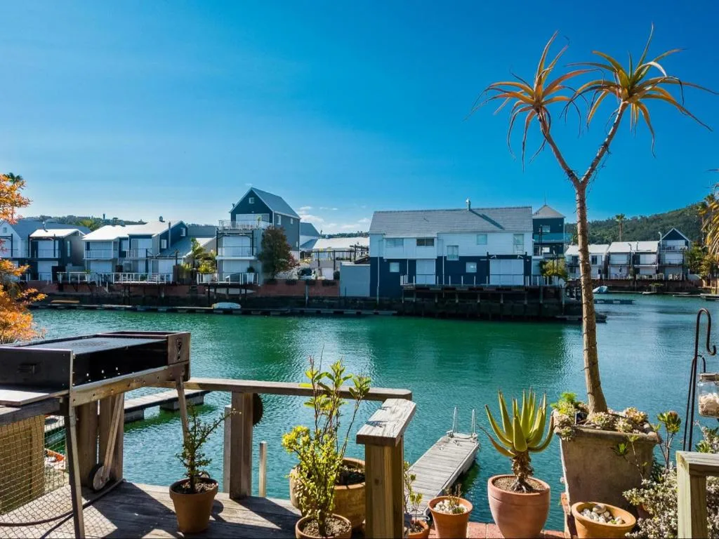 Turquoise lagoon waterfront with colorful boathouses and distant hills
