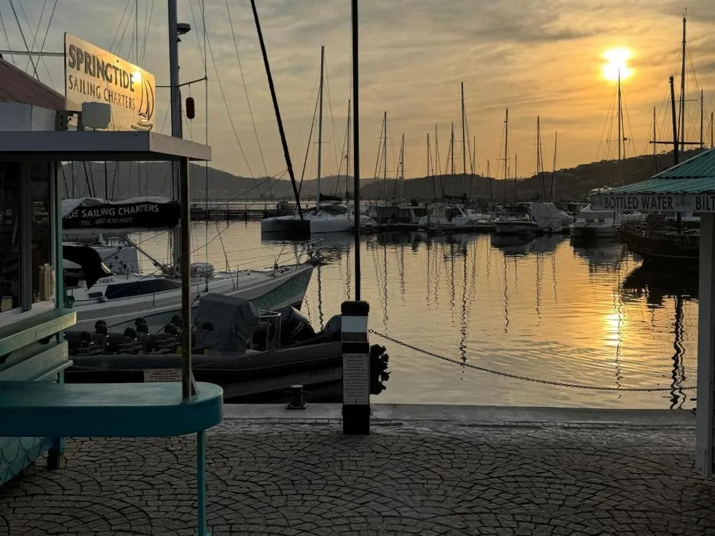 Golden sunset over Knysna harbor with moored sailboats and mountains