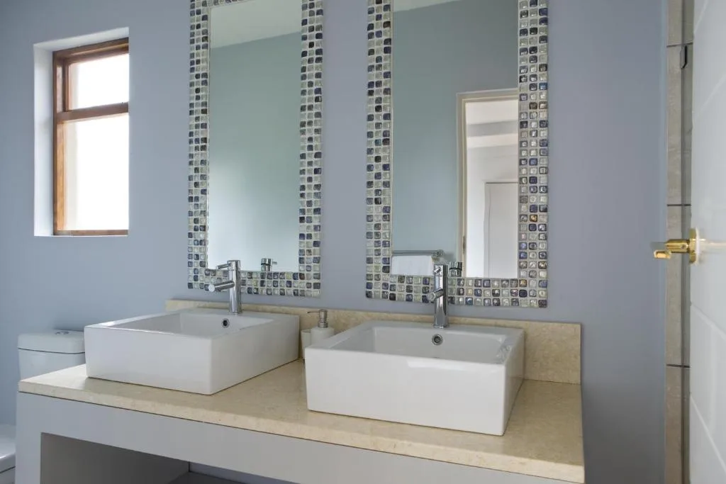Modern bathroom with double vessel sinks and decorative tiled mirror frames