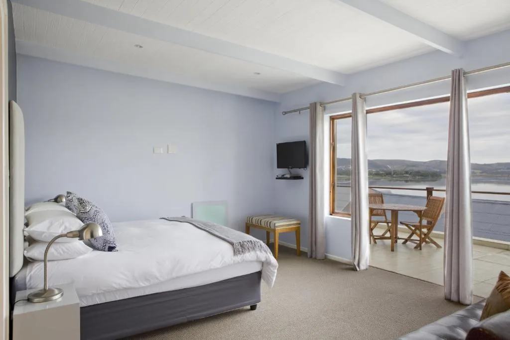 Spacious bedroom with queen bed, mountain and water views through glass doors