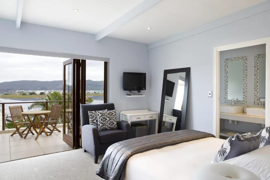 Spacious bedroom with bed, lagoon views through glass doors, and ensuite bathroom