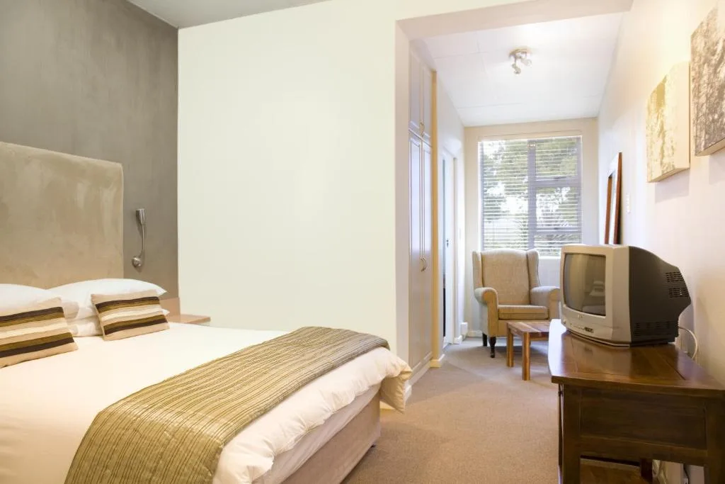 Spacious bedroom with queen bed, striped runner, TV, and seating area