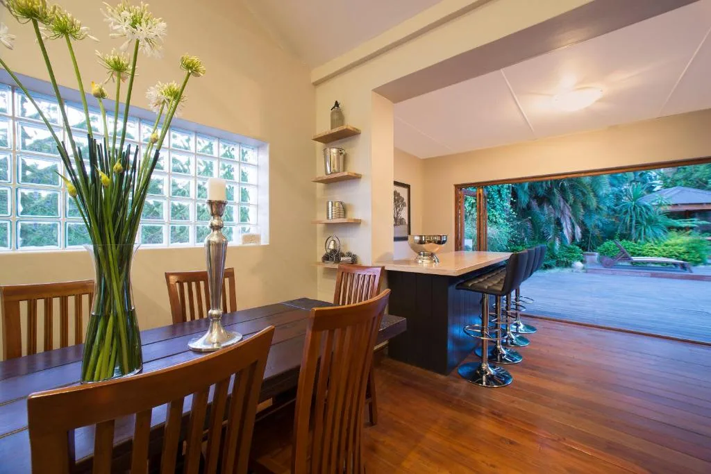 Elegant dining area with wooden table, chairs, and garden views through windows
