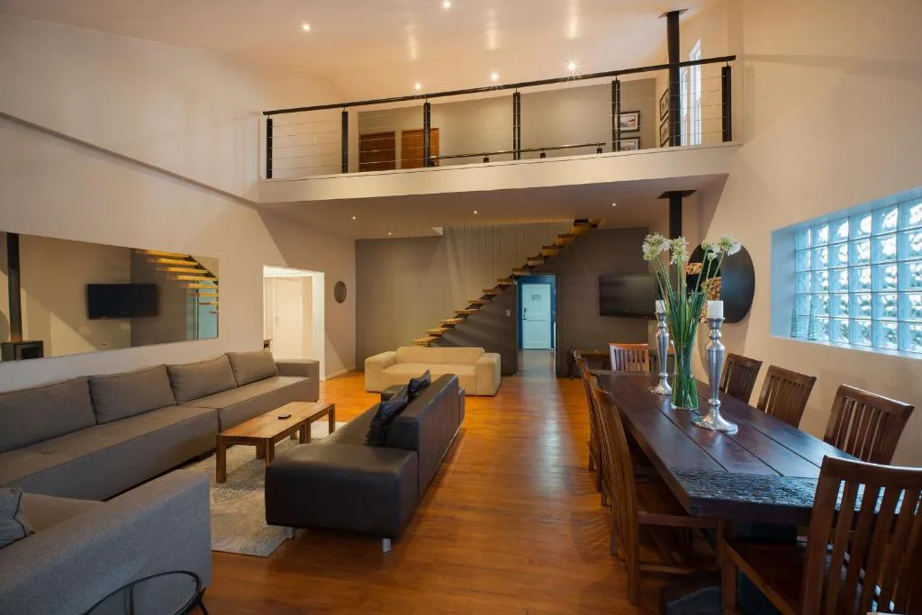 Open-plan lounge with gray sofas, wooden dining table, and mezzanine level above