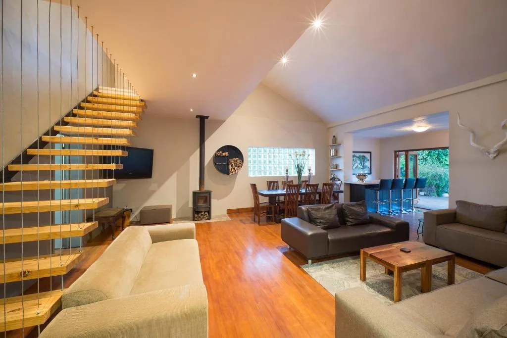 Open-plan lounge with sofas, wooden staircase, and dining area beyond