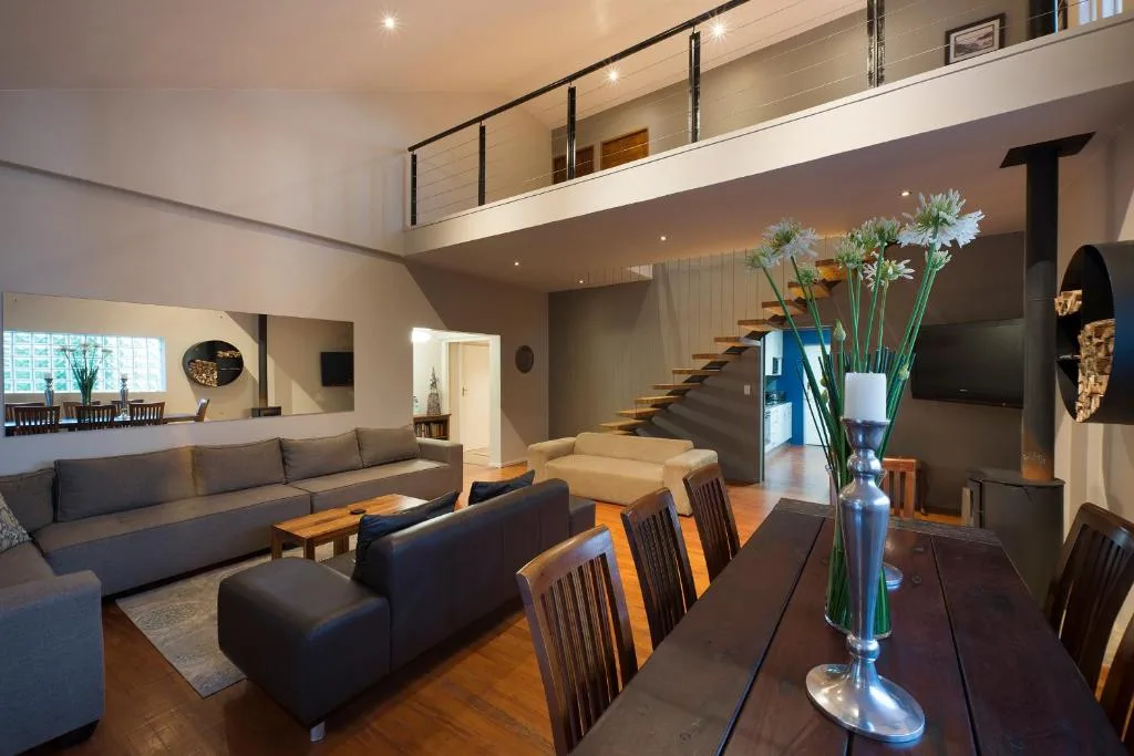 Open-plan lounge with gray sofas, dining table, and modern staircase