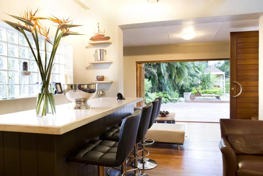 Modern lounge with bar seating, leather chairs, and garden view access