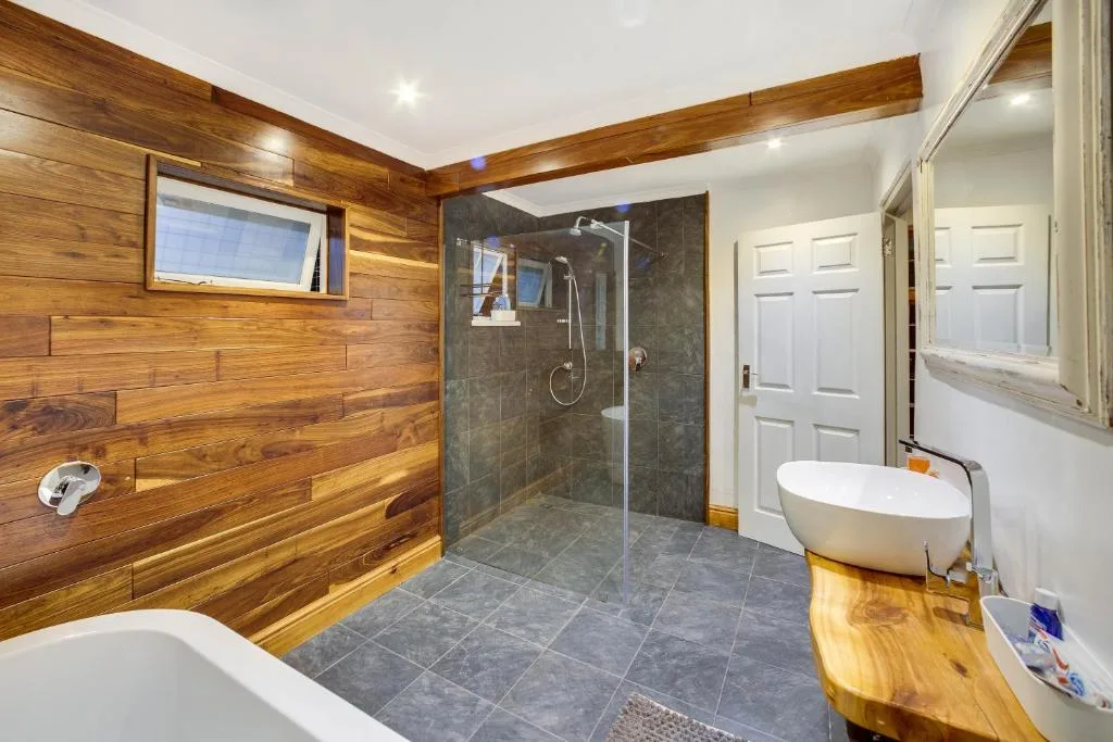 Spacious bathroom with wooden walls, slate tiles, and modern fixtures