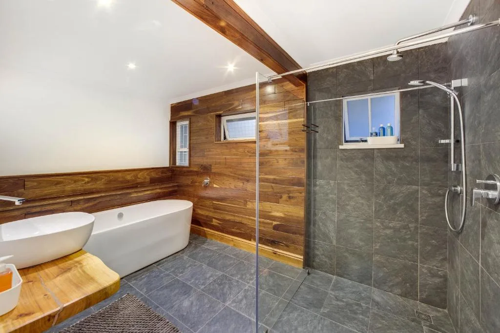 Modern bathroom with freestanding bathtub, walk-in shower, and wooden paneling