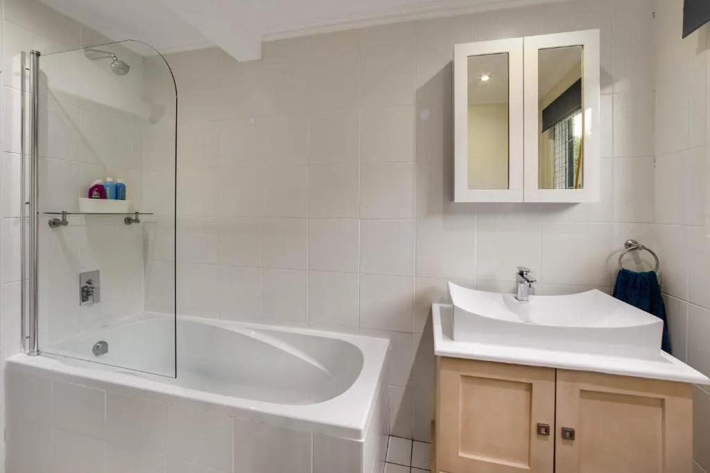 Modern bathroom with walk-in shower, white sink, wooden vanity cabinet