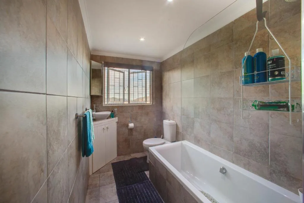 Modern bathroom with white bathtub, vanity sink, and tiled walls