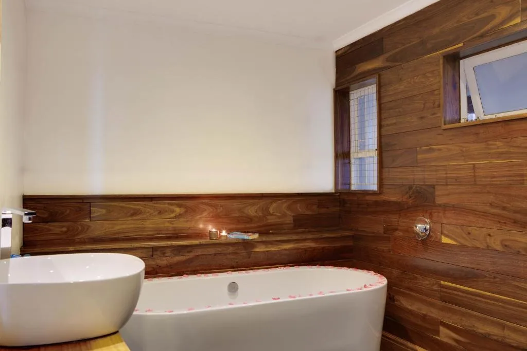 Modern bathroom with freestanding bathtub and round vessel sink against rich wooden paneling