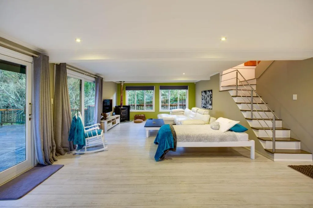 Spacious bedroom with multiple beds, green accent walls, and ocean views through large windows
