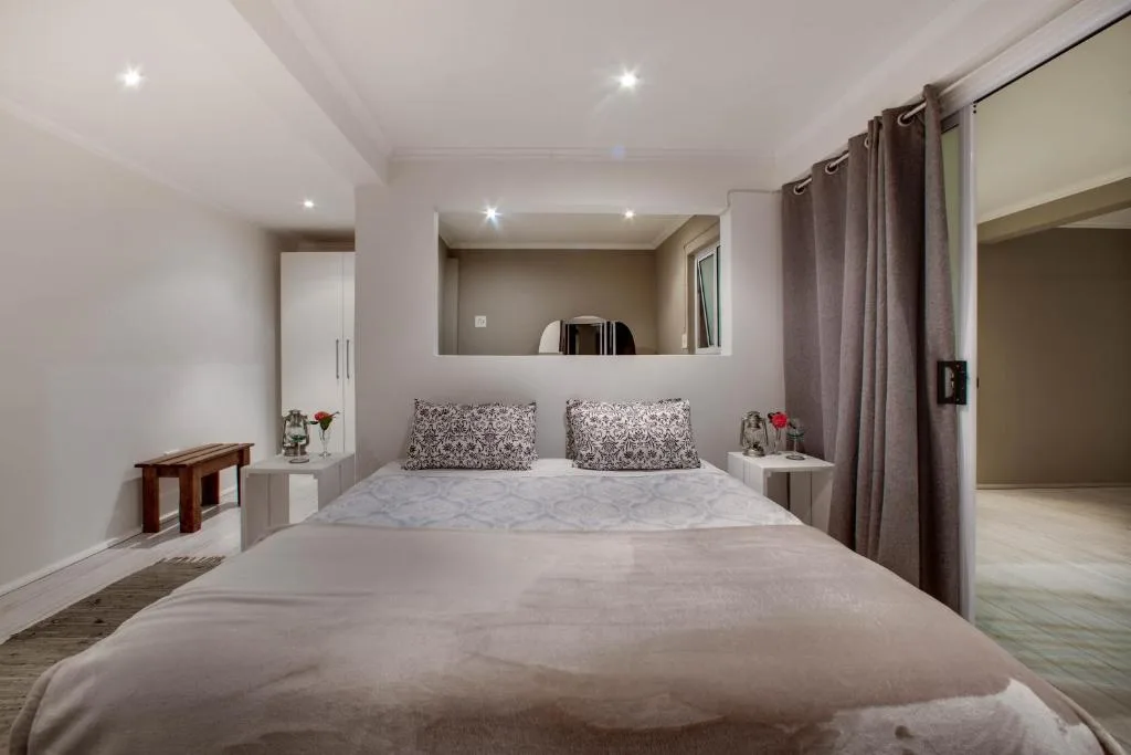 Modern bedroom with queen bed, patterned pillows, and en-suite bathroom view