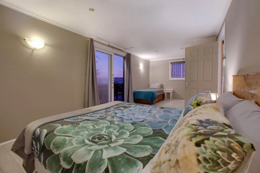 Spacious bedroom with multiple beds and ocean view doors at dusk