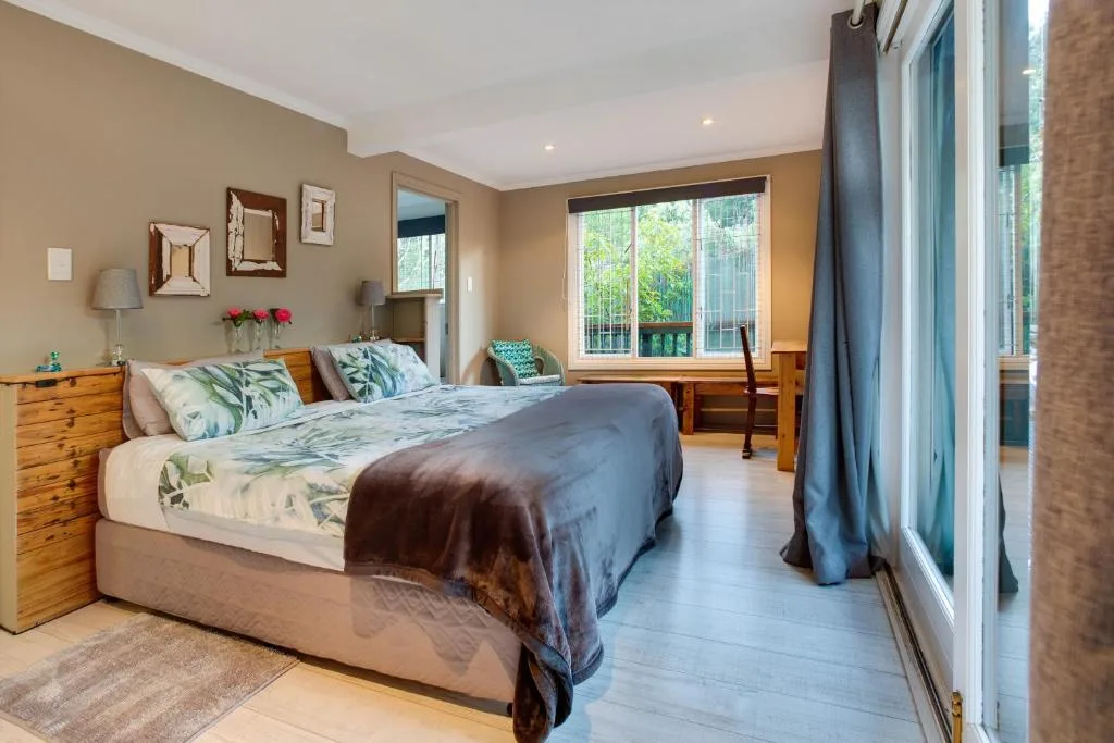 Spacious bedroom with queen bed, wooden furniture, and garden views through large windows