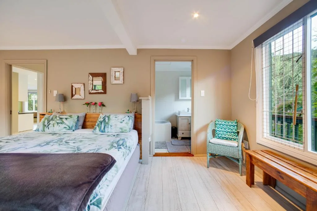 Bright bedroom with queen bed, botanical bedding, and large garden view windows