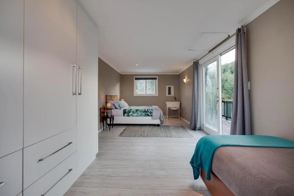 Spacious bedroom with two beds, built-in wardrobe, and glass doors to deck