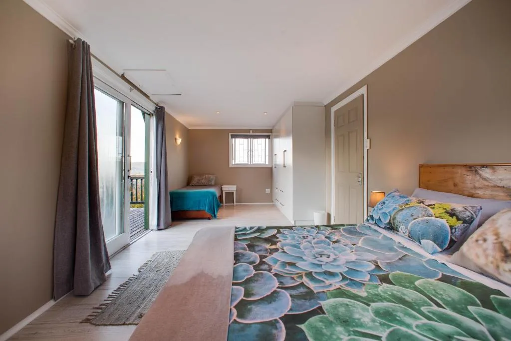 Spacious bedroom with double bed, patio doors, and ocean view access