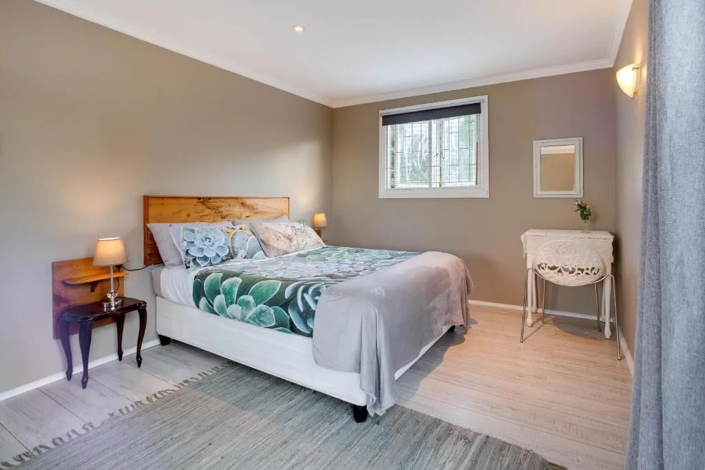Bright bedroom with wooden bed frame and patterned bedding, warm lighting