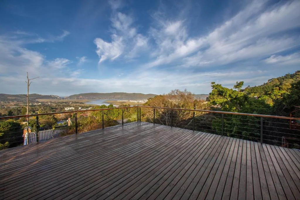 Wooden deck with black cable railing overlooking lagoon and mountains