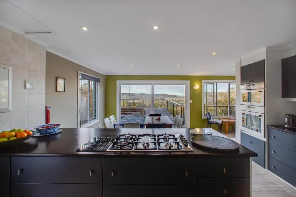 Modern kitchen with gas cooktop, dark island, and scenic mountain views through windows