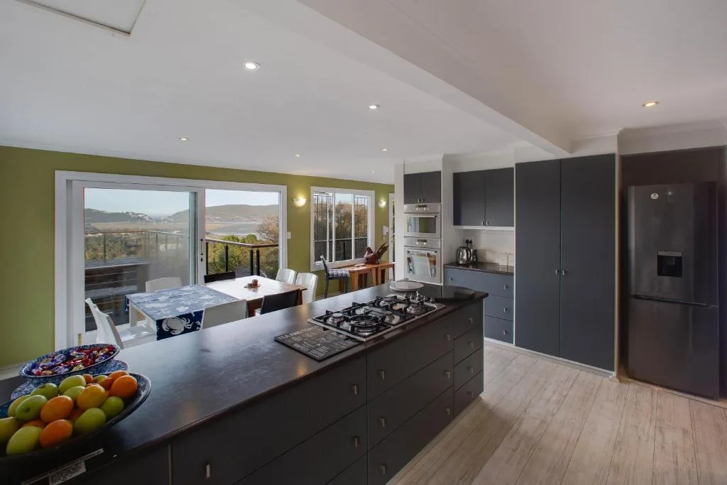 Modern kitchen with gas cooktop, dark cabinetry, and ocean views through large windows