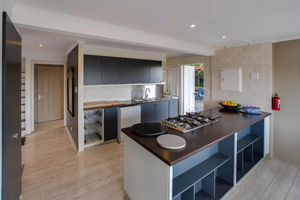 Modern kitchen with dark cabinetry, island cooktop, and stainless steel appliances
