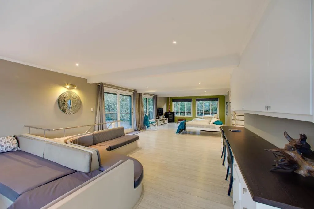 Spacious open-plan lounge with curved seating, wooden floors, and garden views