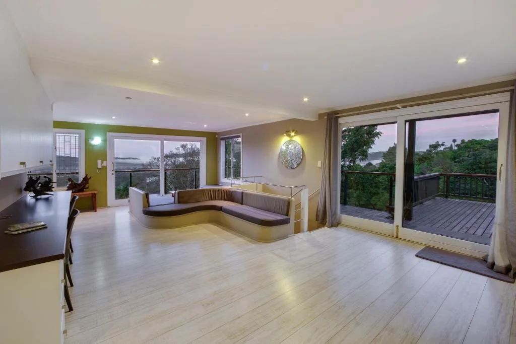 Open-plan lounge with curved seating, water views through large glass doors