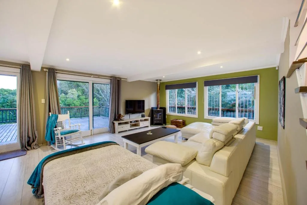 Spacious living room with cream sofa, TV, and forest views through large windows