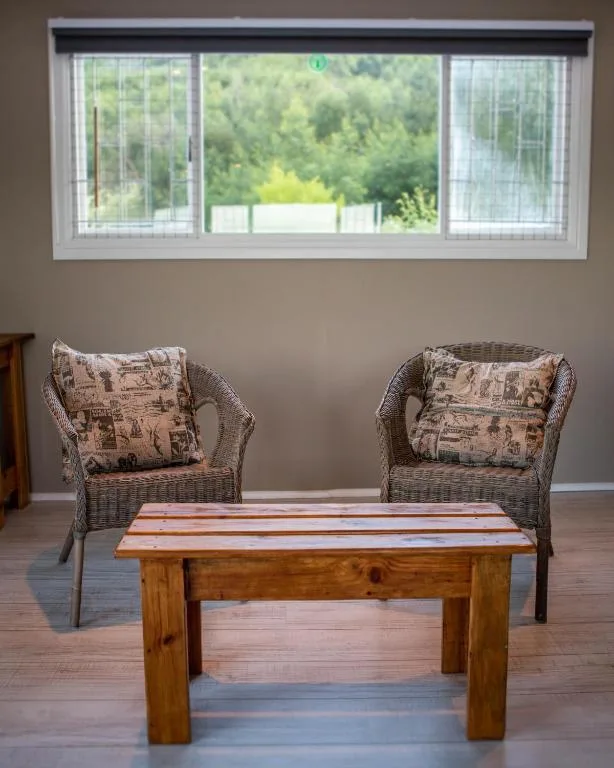 Spacious lounge with wicker chairs, wooden coffee table, and forest views