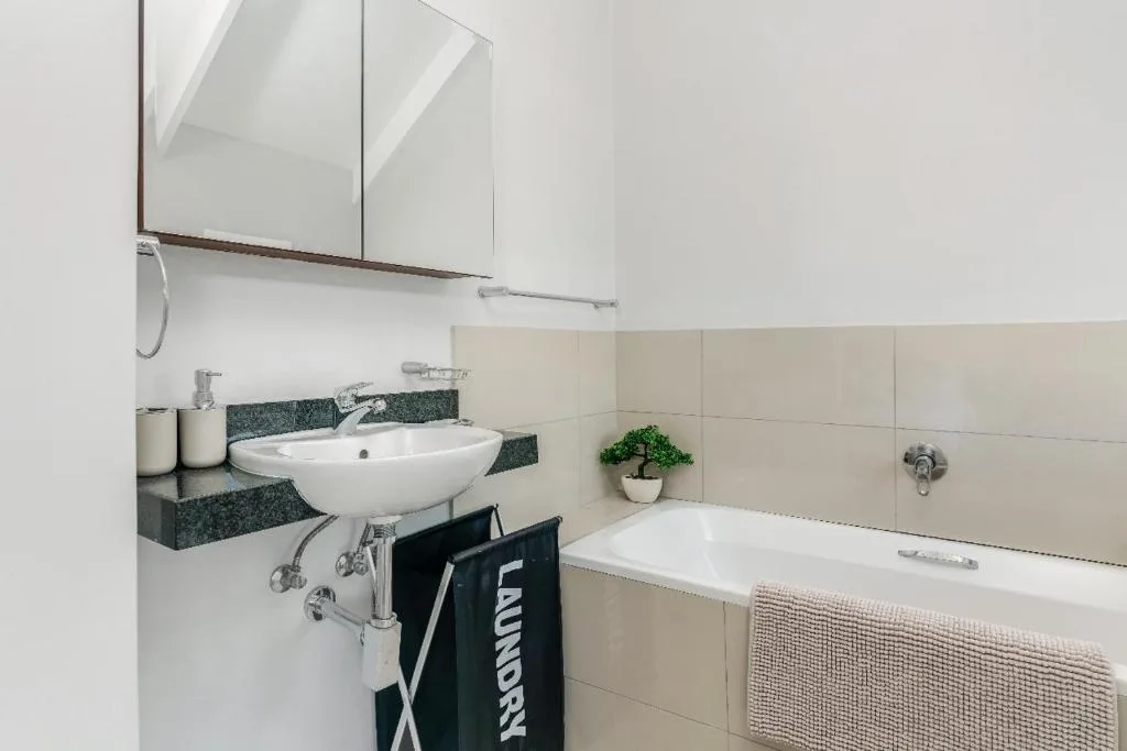 Modern bathroom with white vessel sink, bathtub, and mirrored cabinet