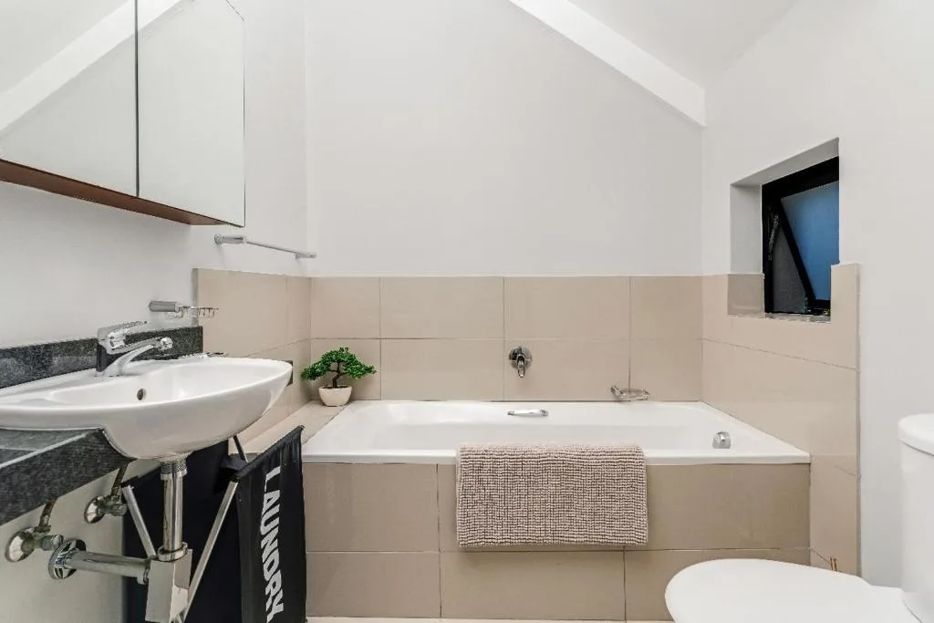 Spacious bathroom with soaking tub, pedestal sink, and vaulted ceiling
